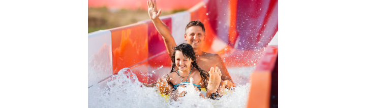 Ein Mann und ein Kind genießen die rasante Fahrt auf einer Wasserrutsche in einem Wasserpark